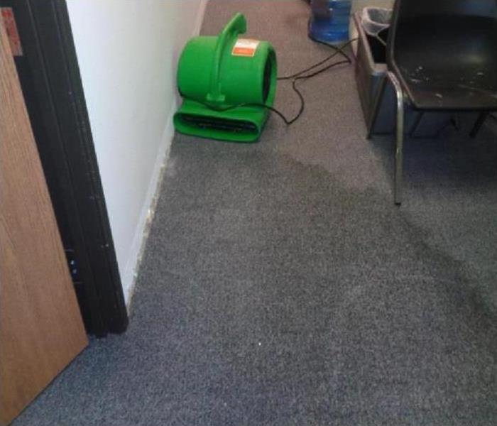 Air mover drying a wet carpet.